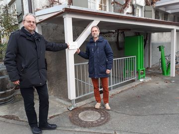 Das Bild zeigt Ralf Stolz und Kai-Steffen Frank wie sie auf die Fördertafel der Fahrradladestation zeigen.ion