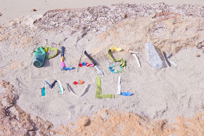 Plastikreste zeichnen das Wort Plastikmüll auf Sandstrand nach