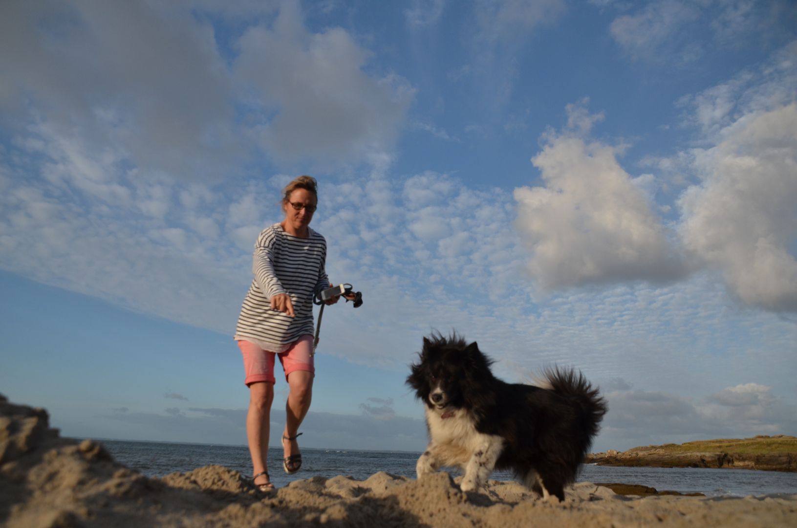 Eine Frau spielt mit ihrem Hund am Strand.