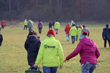 BUND-Aktive schreiten in Regenmontur zu einem Naturschutz-Einsatz.