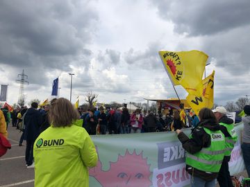 BUND-Aktive halten ein Banner und Fahne bei der Kundgebung vor dem Abschaltfest.