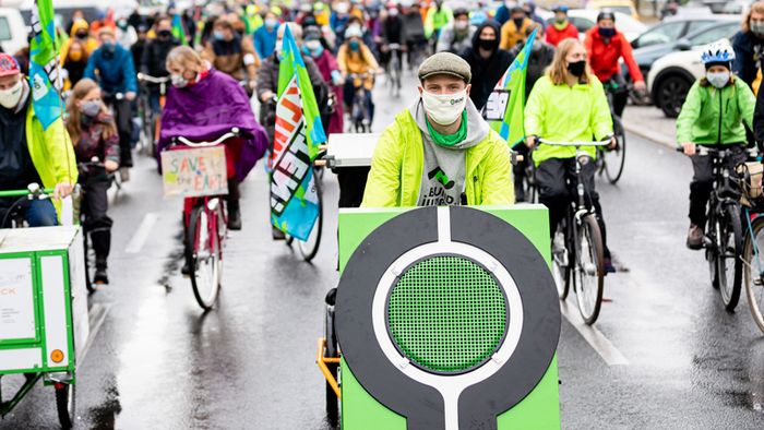 Menschen in grünen Jacken nehmen an einer Fahrraddemo teil.