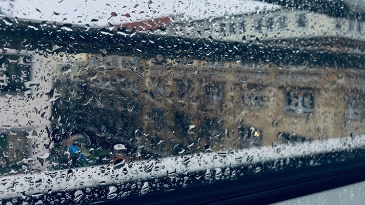 Regen prasselt an eine Fensterscheibe.
