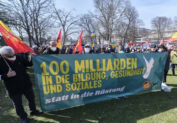 Demonstrierende setzen sich mit einem Plakat gegen die 100 Milliarden für Aufrüstung ein 