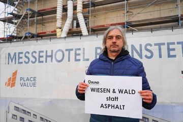 Mann mit "Wiesen und Wald" Schild vor dem Messehotel Rheinstetten