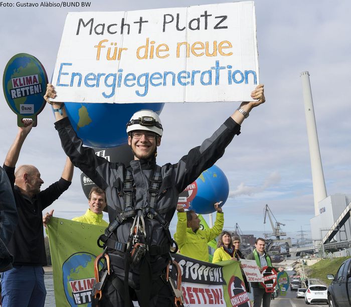 Ein BUND-Aktiver hält bei einer Aktion ein Schild mit "Macht Platz für die Energiewende" in die Höhe