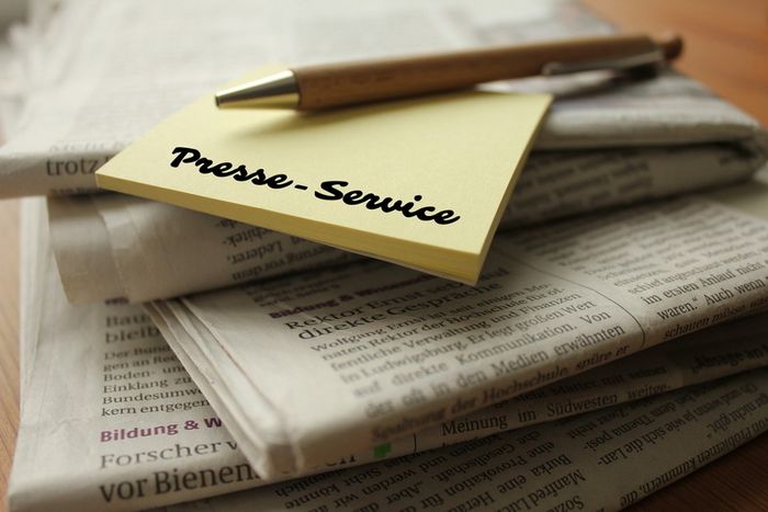 Ein Stapel Tageszeitung mit PostIts und Kugelschreiber.