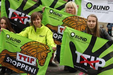BUND-Aktive demonstrieren 2016 mit grünen Flaggen und ernster Mine gegen TTIP.