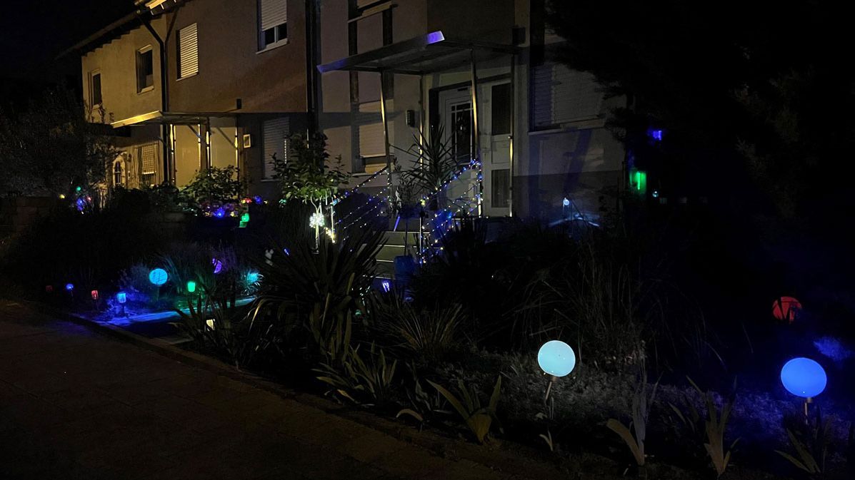 Vorgarten mit leuchtenden Dekoleuchten in der Nacht.