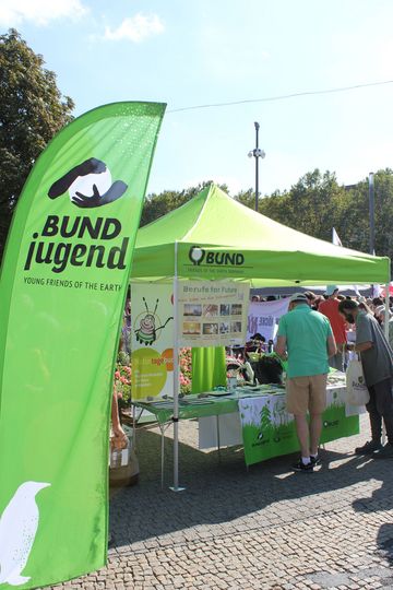 BUNDjugend Fahne weht vor einem Infostand des BUND.