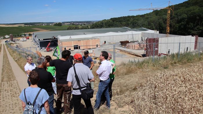BUND-Aktive schauen von einem Hügel hinunter auf die Pilzland-Baustelle.ner (B90/Grüne) übt der BUND Baden-Württemberg erneut scharfe Kritik an der laschen Genehmigungspraxis für große Industrieanlagen außerhalb von Baugebieten.