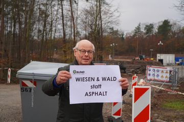 Ein Mann mit "Wiesen und Wald" Schild auf Baustelle