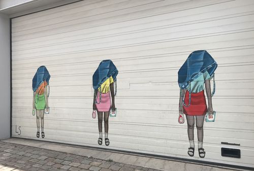 Ein Graffiti auf einer Garagentür zeigt drei Personen mit Plastiktüten über dem Kopf