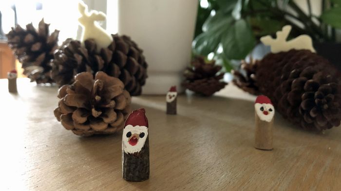 Tannenzapfen und kleine Weihnachtmänner aus Holz auf einem Tisch als Dekoration