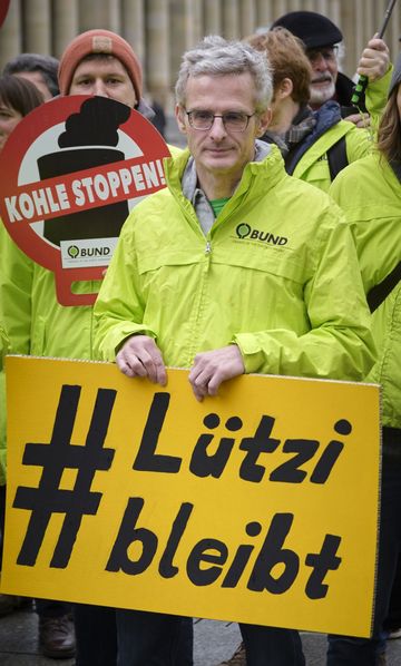 BUND-Landesgeschäftsführer Martin Bachhofer trägt ein Schild "Lützi bleibt".