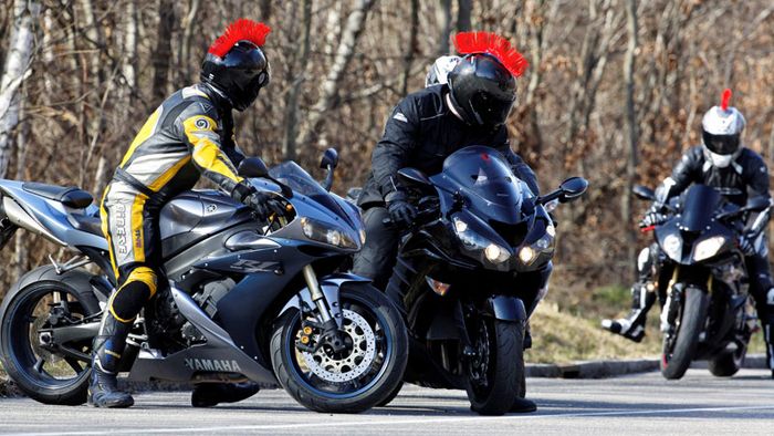 Drei Motorradfahrer stehen am Straßenrand mit ihren Fahrzeugen.