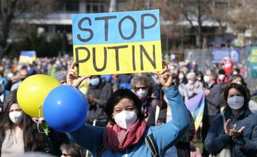 Eine Demonstrantin hebt ein "Stop Putin" Plakat in die Luft.