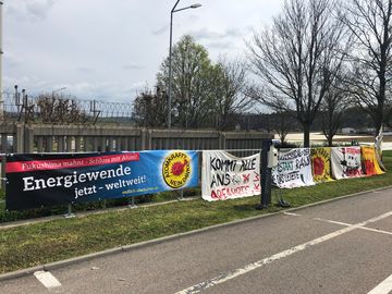 An einem Zaun sind verschiedene Plakate der Umweltbewegungen gegen Atomkraft angebracht.
