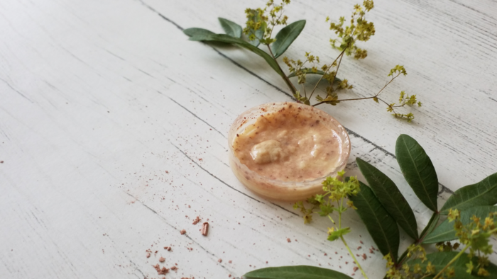 Ein Creme-Tiegel auf einem Holzboden mit Puder und Pflanzen