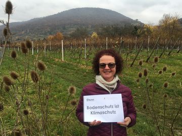 Frau mit "Bodenschutz ist Klimaschutz" Schild 