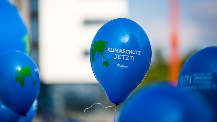 Ein blauer Luftballon mit der Aufschrift Klima schützen jetzt auf einer Demo.