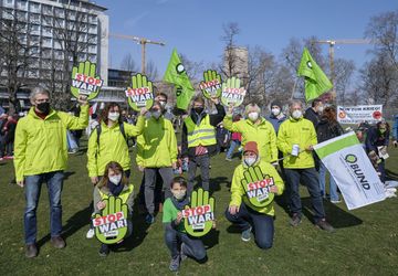 Mitarbeitende des BUND demonstrieren mit grünen Jacken und Fahnen
