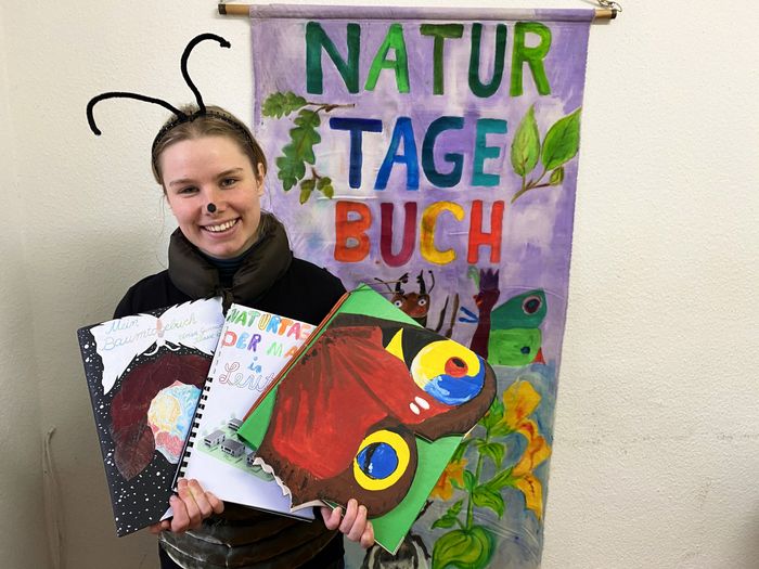 Manfred Mistkäfer hält Naturtagebücher in den Händen.
