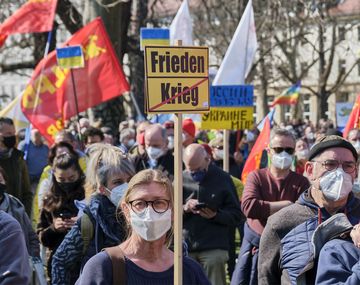 Eine Frau demonstriert mit einem "Frieden statt Krieg" Schild.
