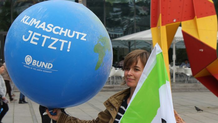BUND-Mitglied mit einem blauen Luftballon mit der Aufschrift "Klimaschutz jetzt""