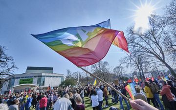 Eine Regenbogenflagge mit PACE Aufschrift weht auf der Demo