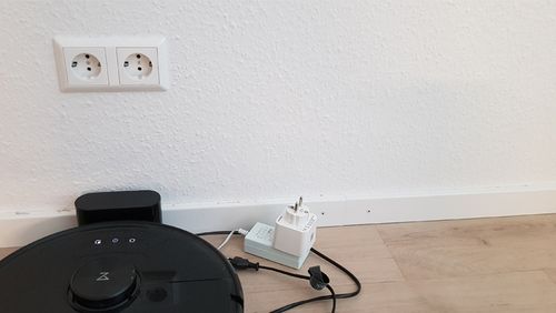 Ein Staubsaugroboter mit Stromstecker. 