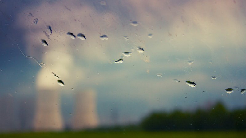 Ein verschwommenes AKW hinter Glas mit Regentropfen auf der Scheibe.