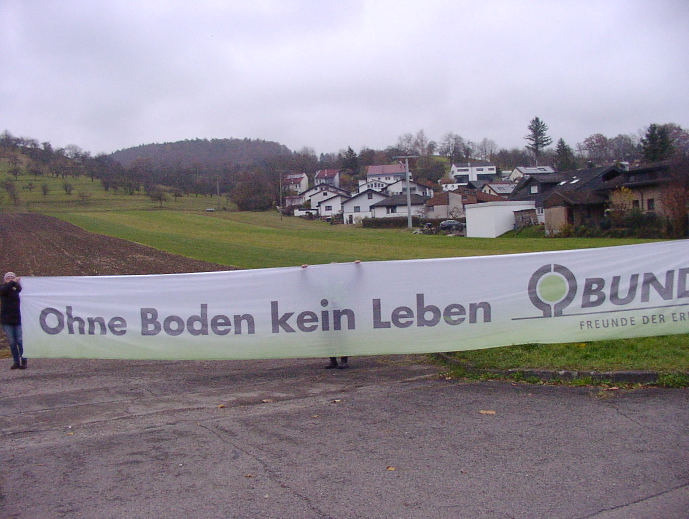 "Ohne Boden kein Leben" Banner vor einer Wiese