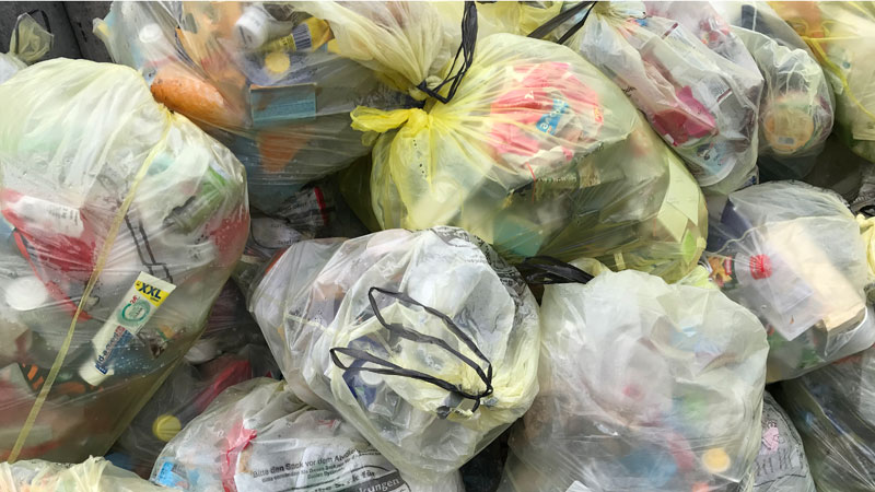 Prallgefüllte Plastikmüllsäcke liegen am Straßenrand.